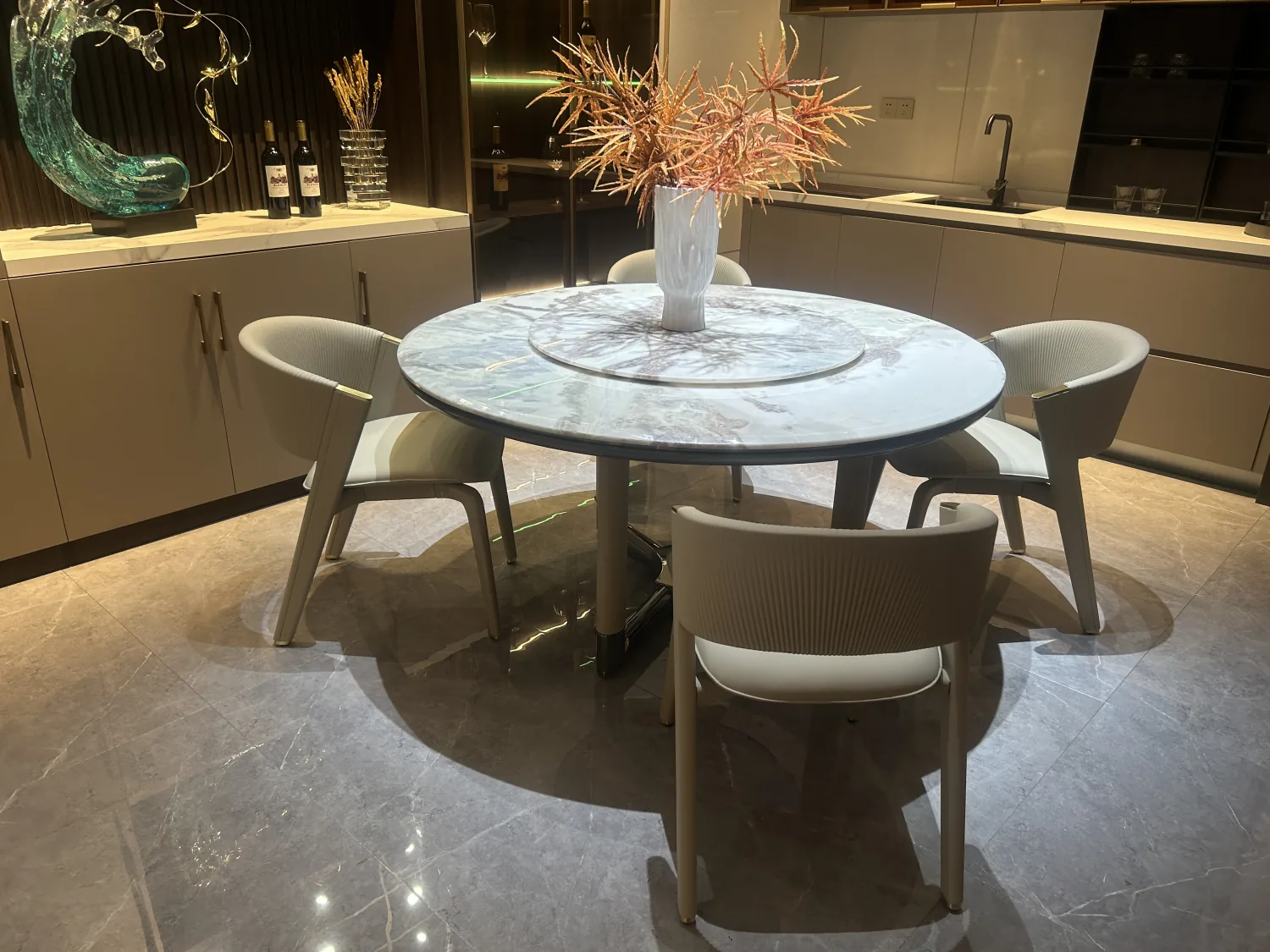 Showroom dining area with a round stone table and upholstered chairs